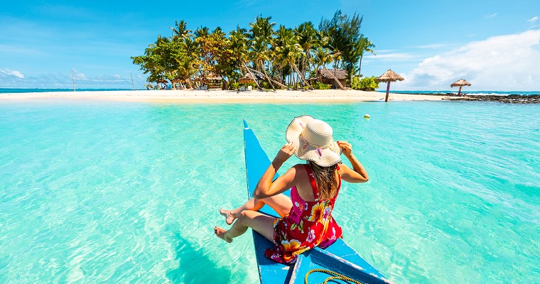 Woman sitting on bangka boat approaching a tropical island