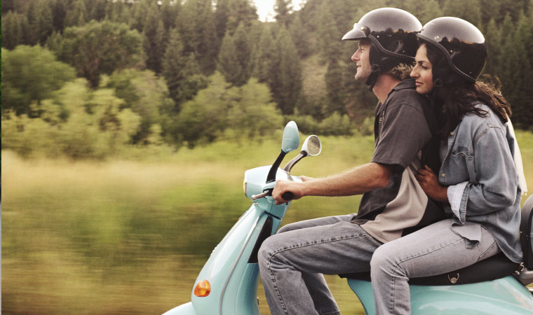 Two people wearing helmets riding on a motorcycle