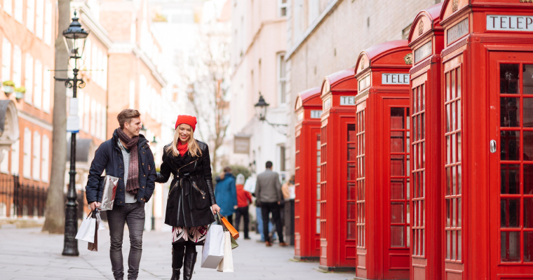 A couple walking in front of red phone boxes in London