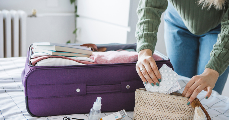 A person packing medication into a suitcase