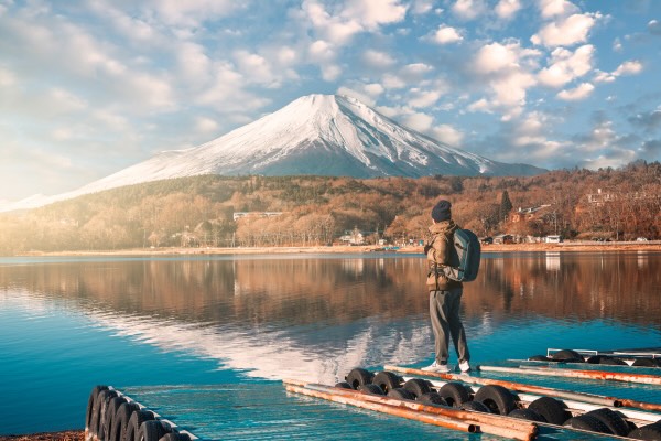 Rear View Of Man discovering beautiful Mt. Fuji By Lake Against Mt Fuji In Winter