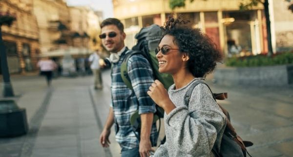 two travellers walking while smiling with a backpack