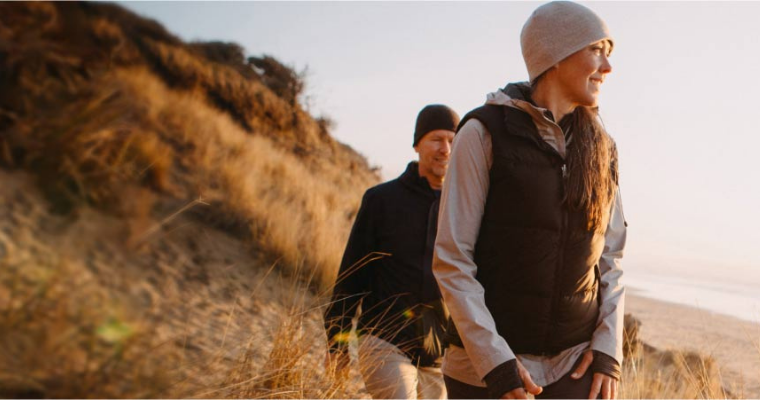 A coupla walking on sand dunes at the beach