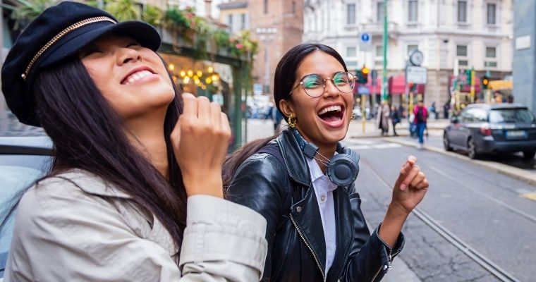 Two women laughing on the street in a European city