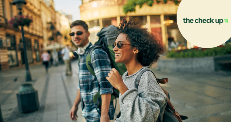 two travellers walking while smiling with a backpack