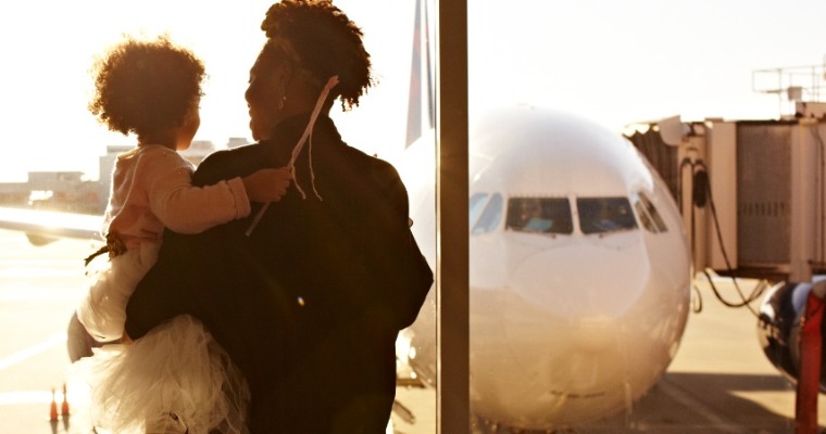 A woman and a child at the airport looking out the window at a plane