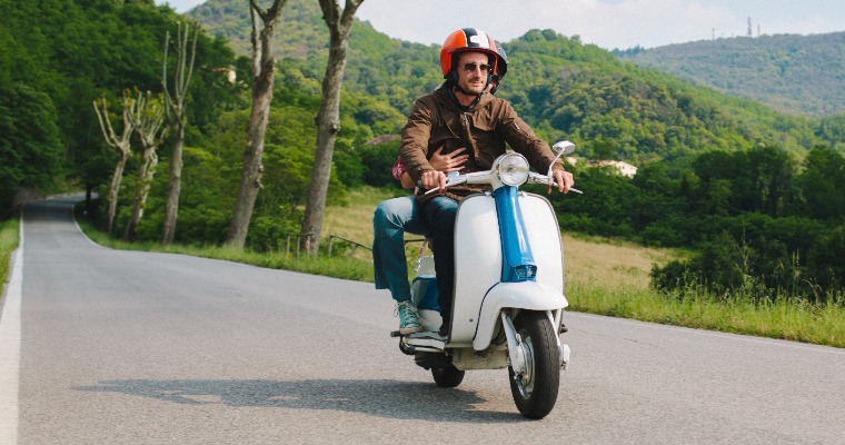 A man riding on a moped with a helmet on