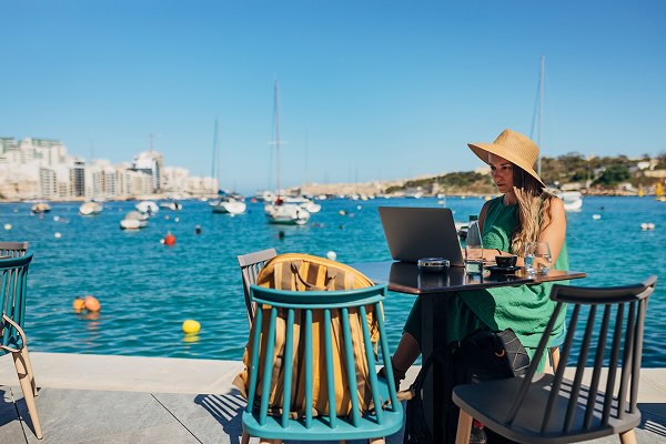 A digital nomad working on a laptop in a picturesque location